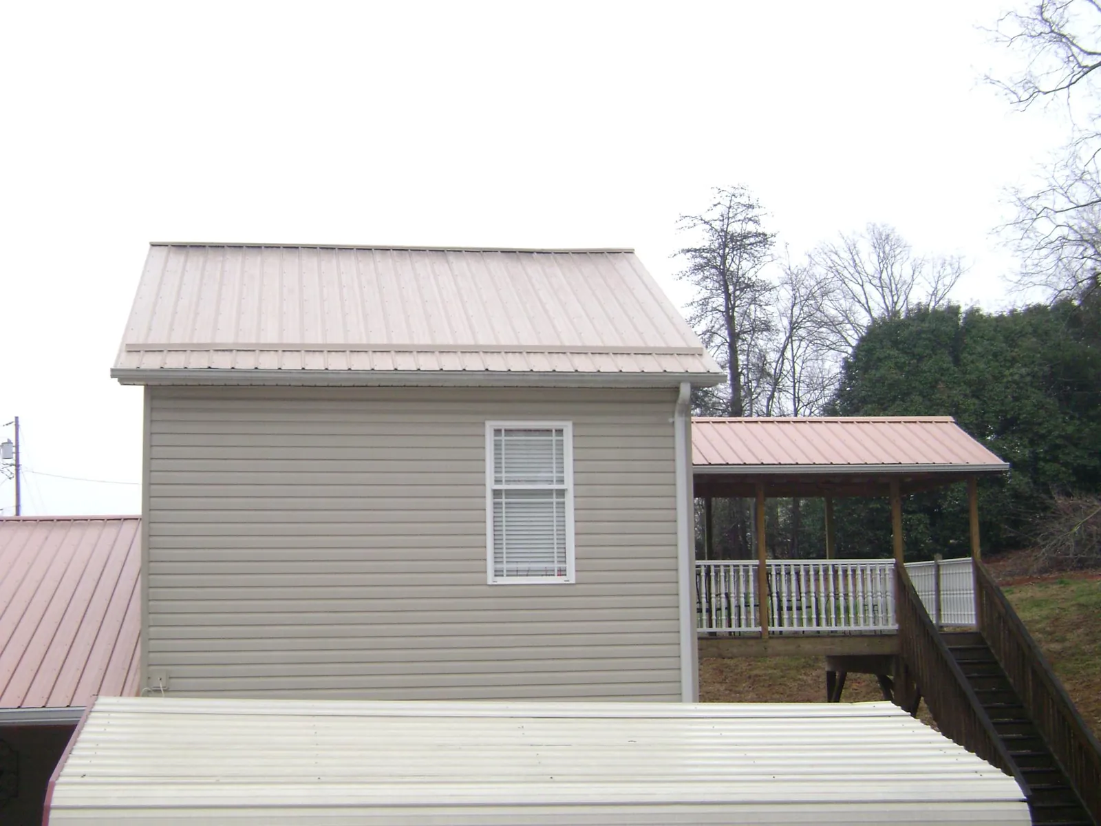 Tan metal roofs on a two story addition and attached porch, from a Roof Replacement job in Livermore